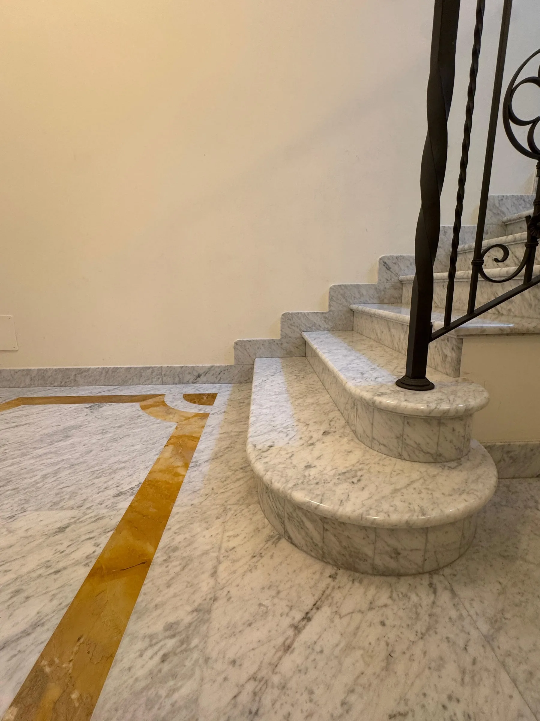 Escalier courbe en Bianco Carrara avec bande de Giallo Siena