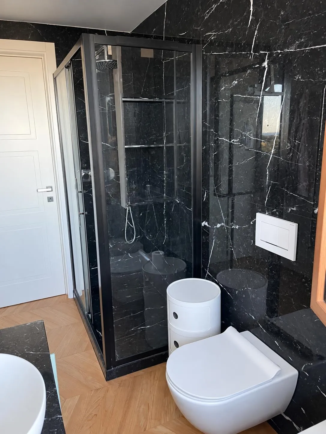 Book-matched Nero Marquina bathroom with glass shower