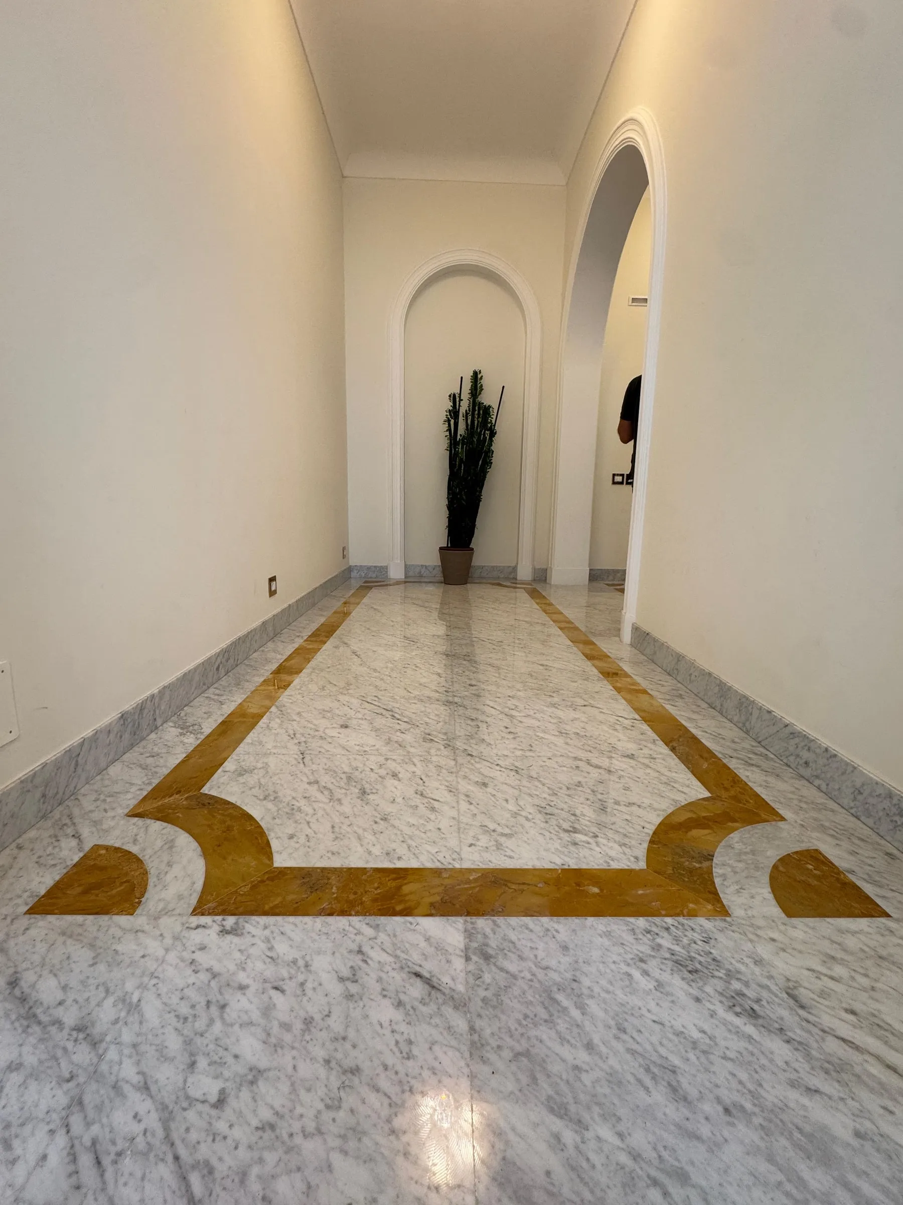 Couloir avec sol en Bianco Carrara et bordure en marqueterie de Giallo Siena