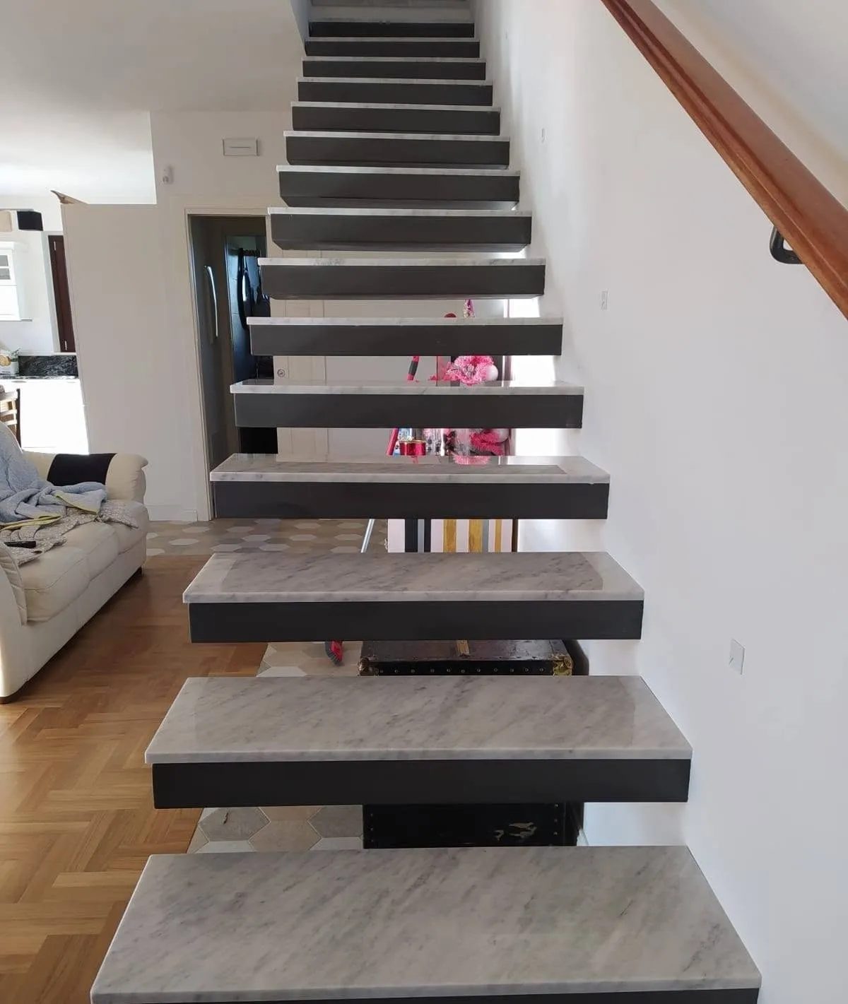 Cantilevered staircase with grey marble treads on a blackened steel frame