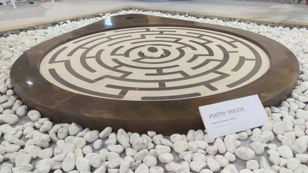 Shower base with a labyrinth motif inlaid in contrasting marbles