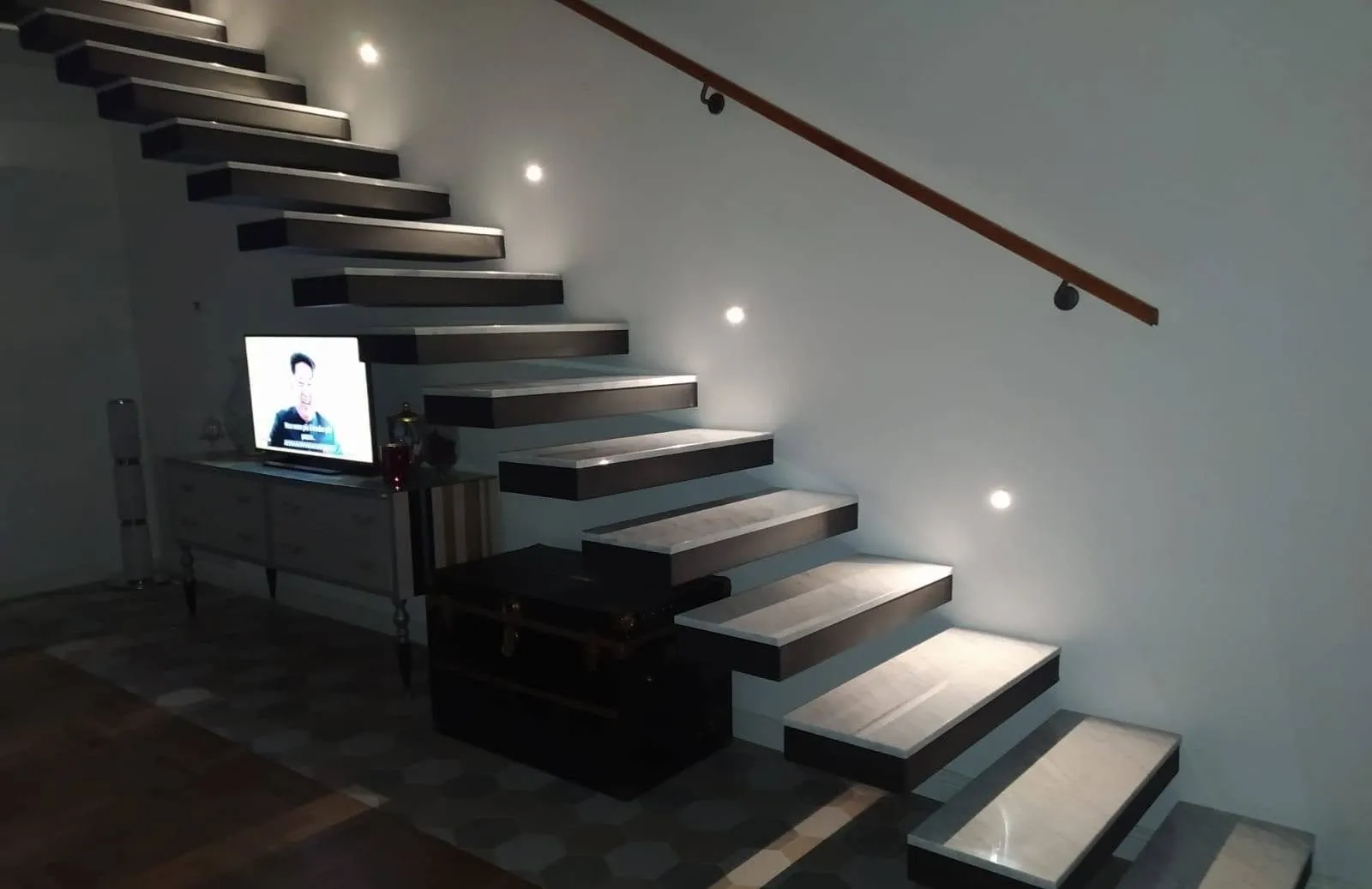 Scala a sbalzo in marmo grigio con luci a parete