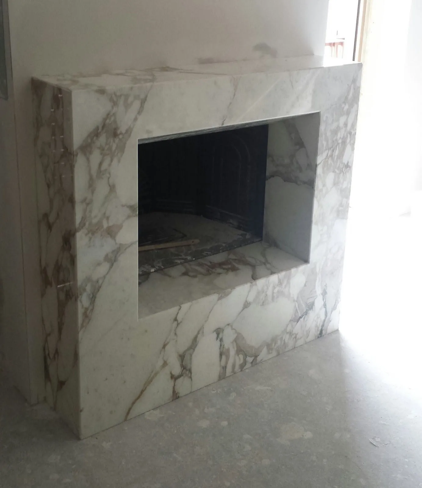 Block fireplace in veined white marble