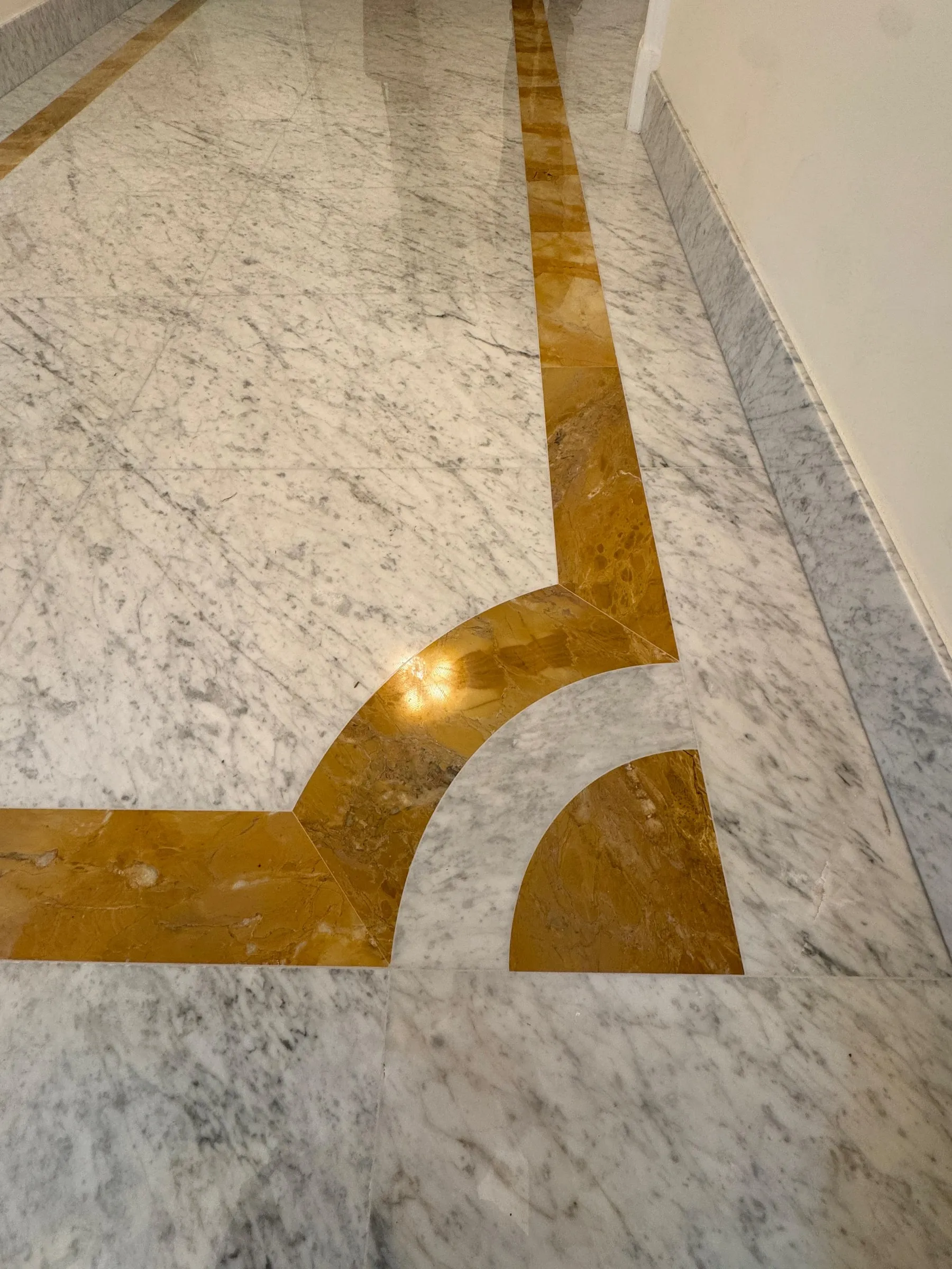 Fascia curva in Giallo Siena nel pavimento in Bianco Carrara