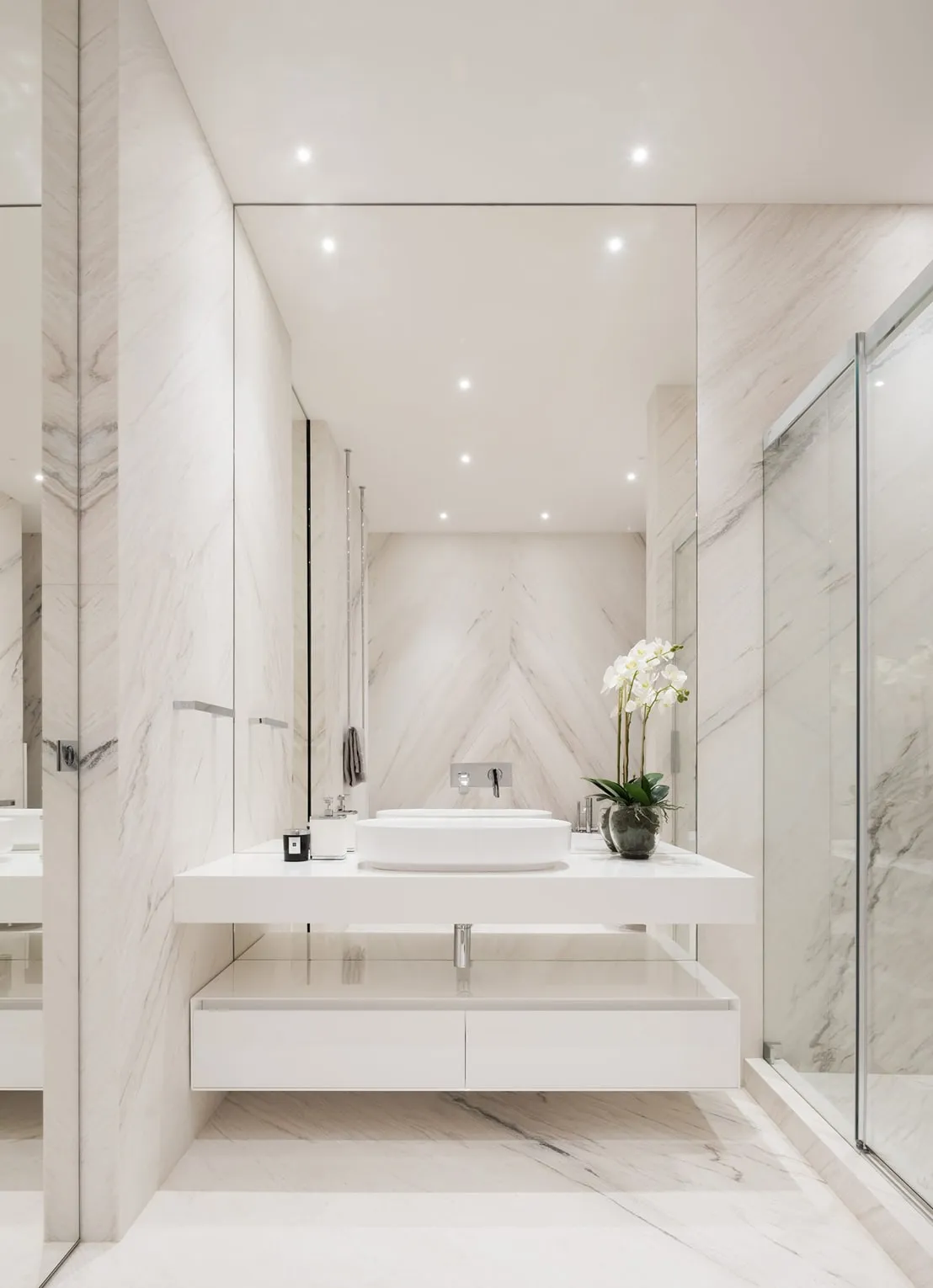 White marble bathroom with a floating vanity top and glass shower